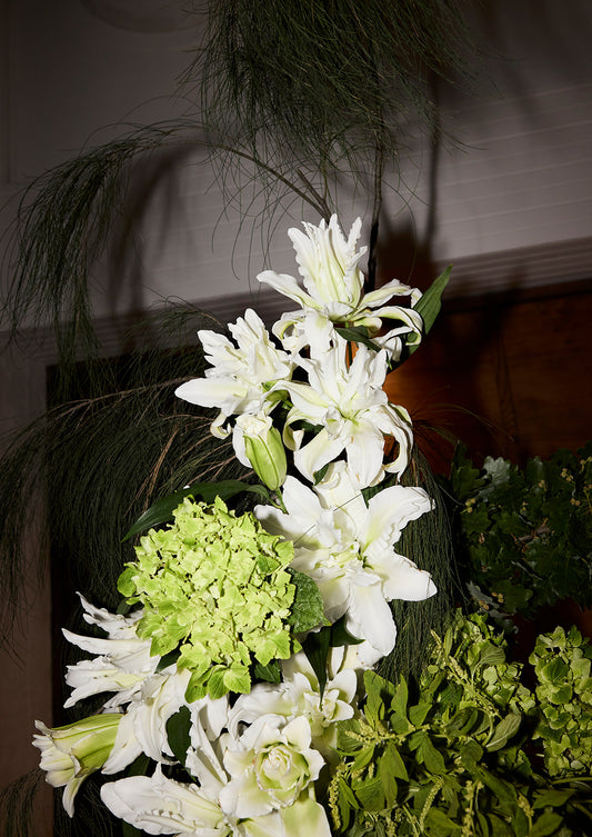 White lilies, green hydrangea and trailing grasses in a reception floral arrangement — wedding table styling, Just Hitched