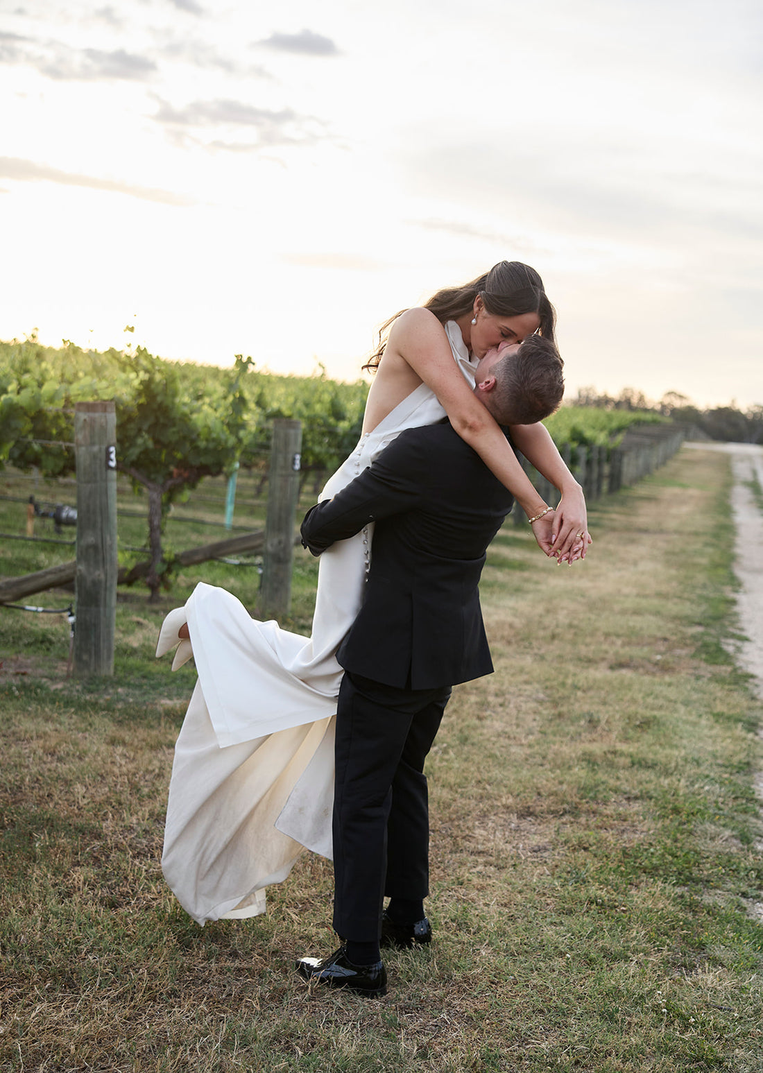 A bride and groom embrace at golden hour among the vines at their Australian vineyard wedding — Just Hitched