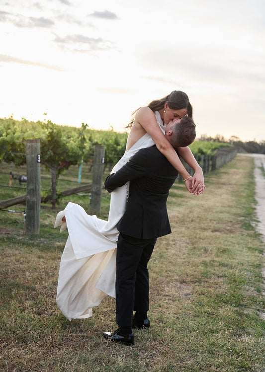 A bride and groom embrace at golden hour among the vines at their Australian vineyard wedding — Just Hitched